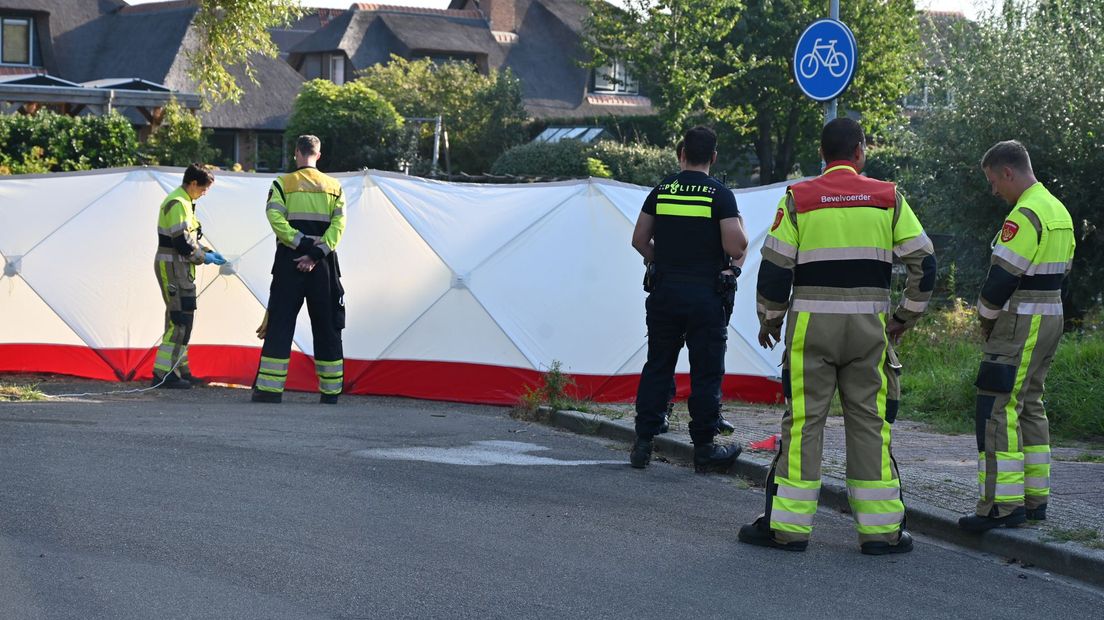In de straat zijn witte schermen geplaatst rond het lichaam.