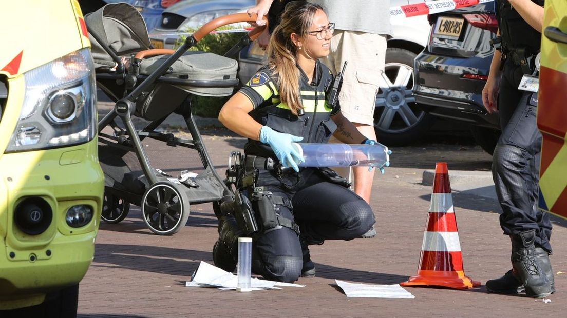 Een agente stelt het gebruikte mes veilig. Op de achtergrond de kinderwagen.