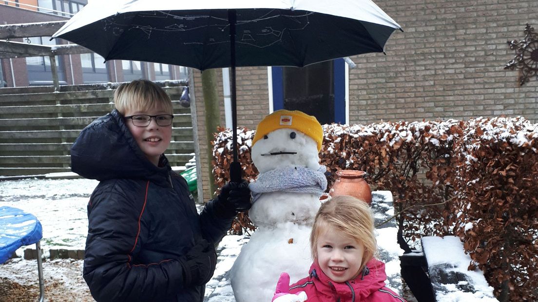 Hero (10) en Wende (6) uit Bedum beschermen hun sneeuwpop tegen de regen.