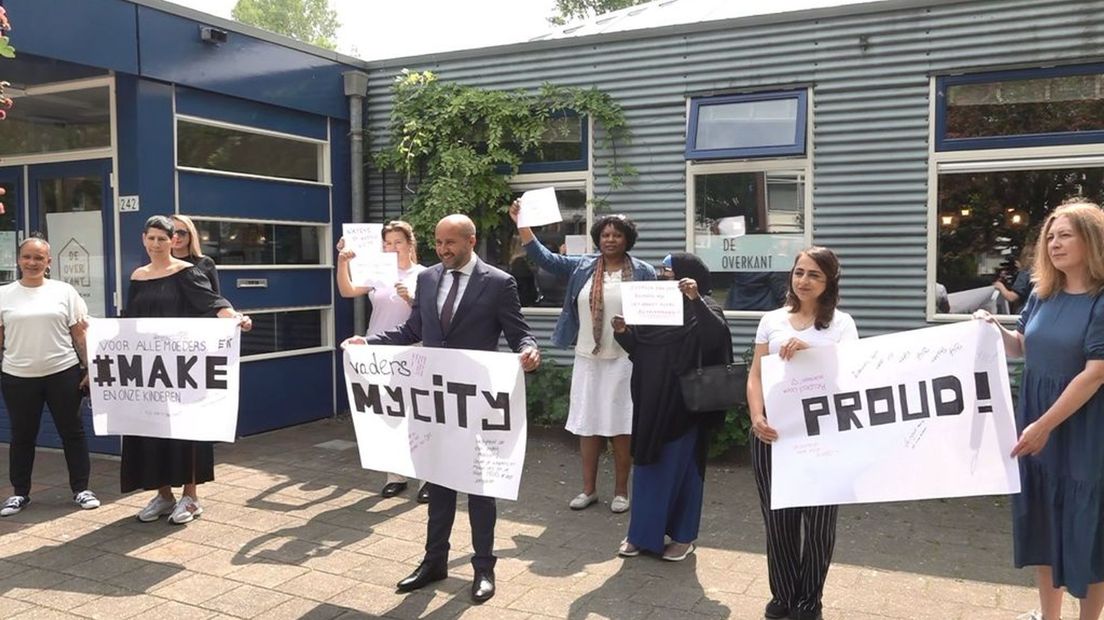 De moeders tonen hun spandoeken samen met burgemeester Ahmed Marcouch.