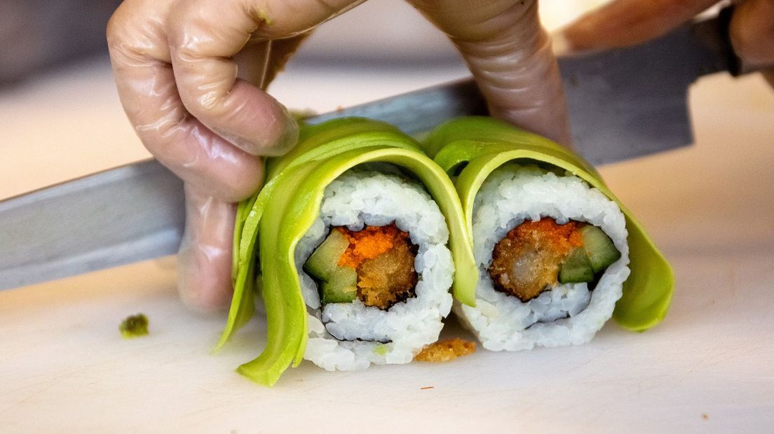 Na het rollen van de rijst wordt sushi in plakjes gesneden