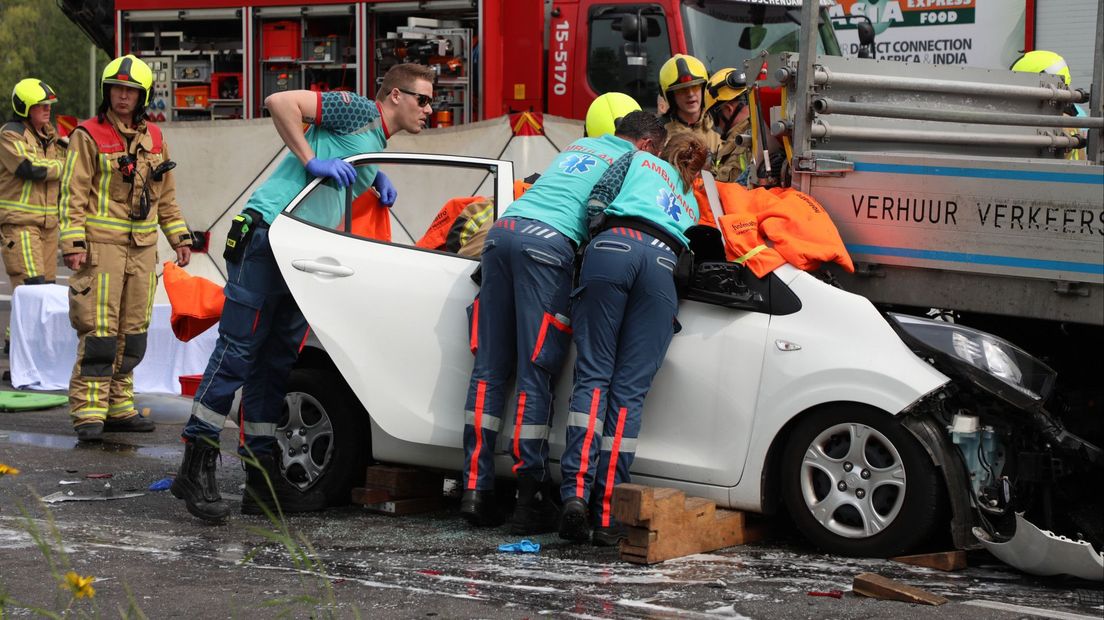 Hulpverleners proberen het slachtoffer uit de auto te bevrijden