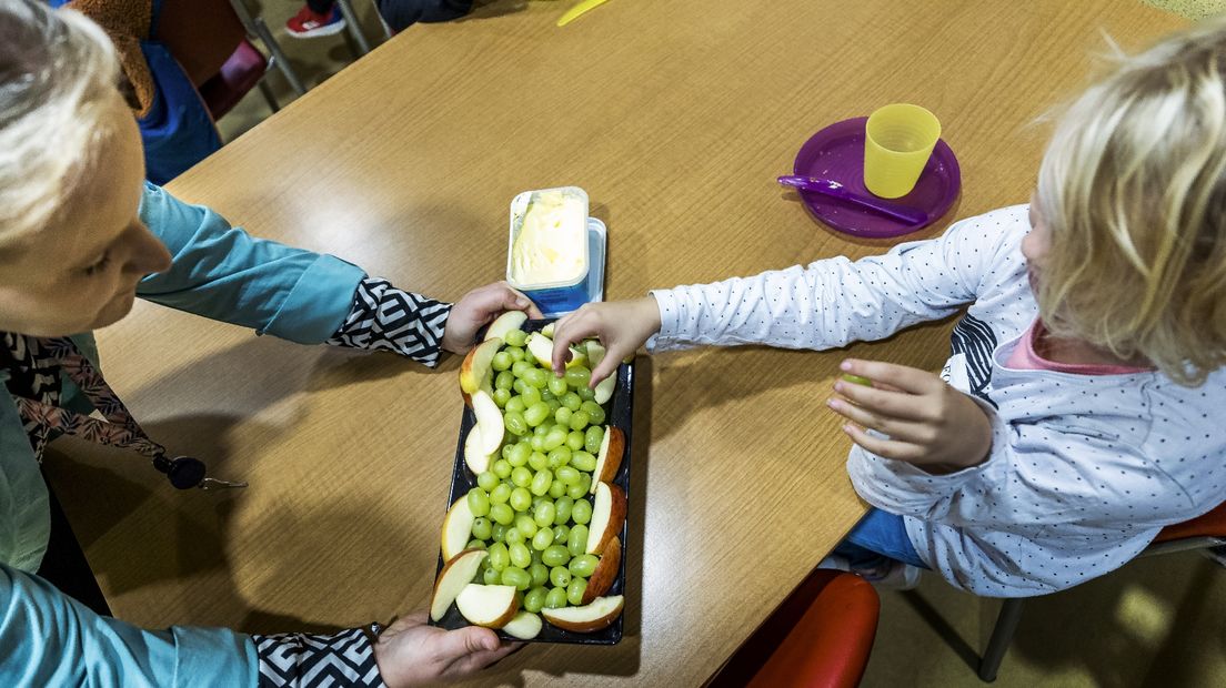 Een leerling pakt een aantal druiven tijdens een schoolontbijt