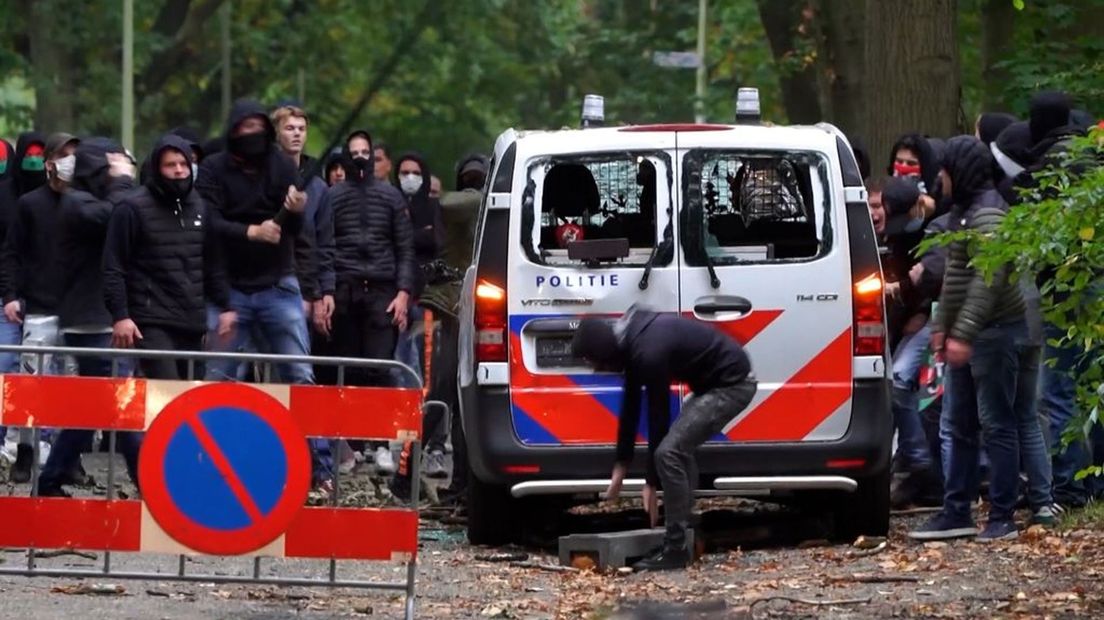 Relschoppers vernielen een politiebusje tijdens de rellen na de wedstrijd NEC-Vitesse.