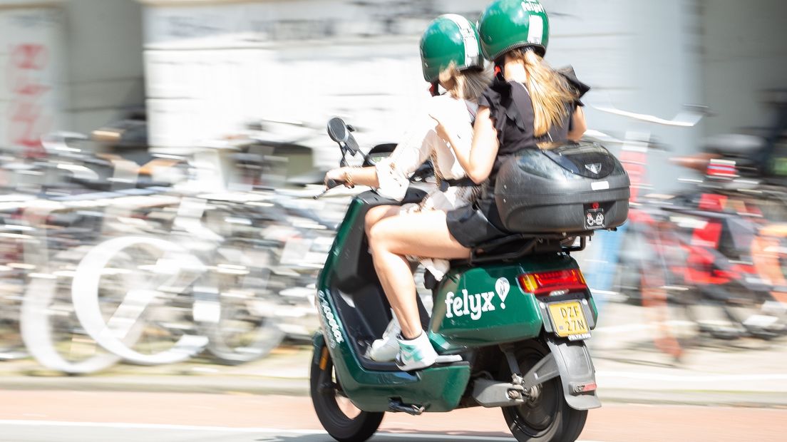 Twee gebruikers van een Felyx deelscooter dragen een helm