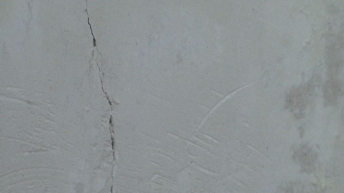 Achter het behang ontdekte een bewoner een flinke scheur in de muur.