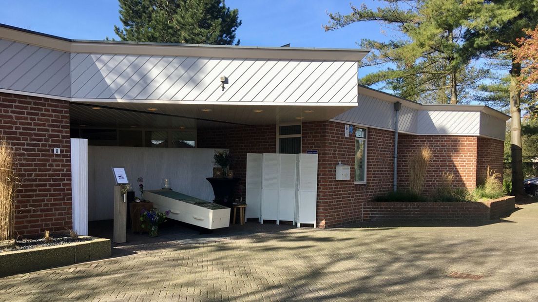 De kist staat bij een drive-in condoleance buiten onder een afdak.