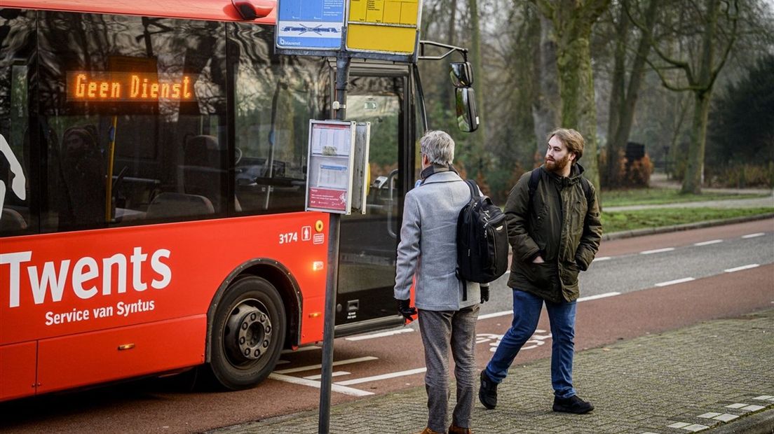 Een bus passeert wachtende reizigers op het station van Delden tijdens een staking van het streekvervoer en regionaal vervoer.