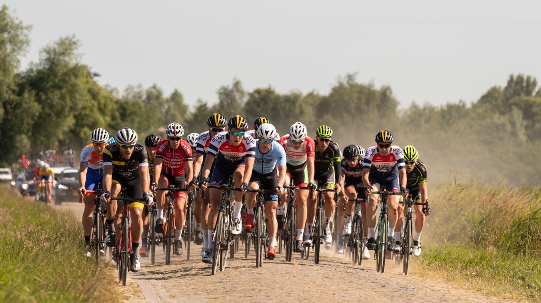 Het peloton over de kasseien rond Philippine tijdens het NK