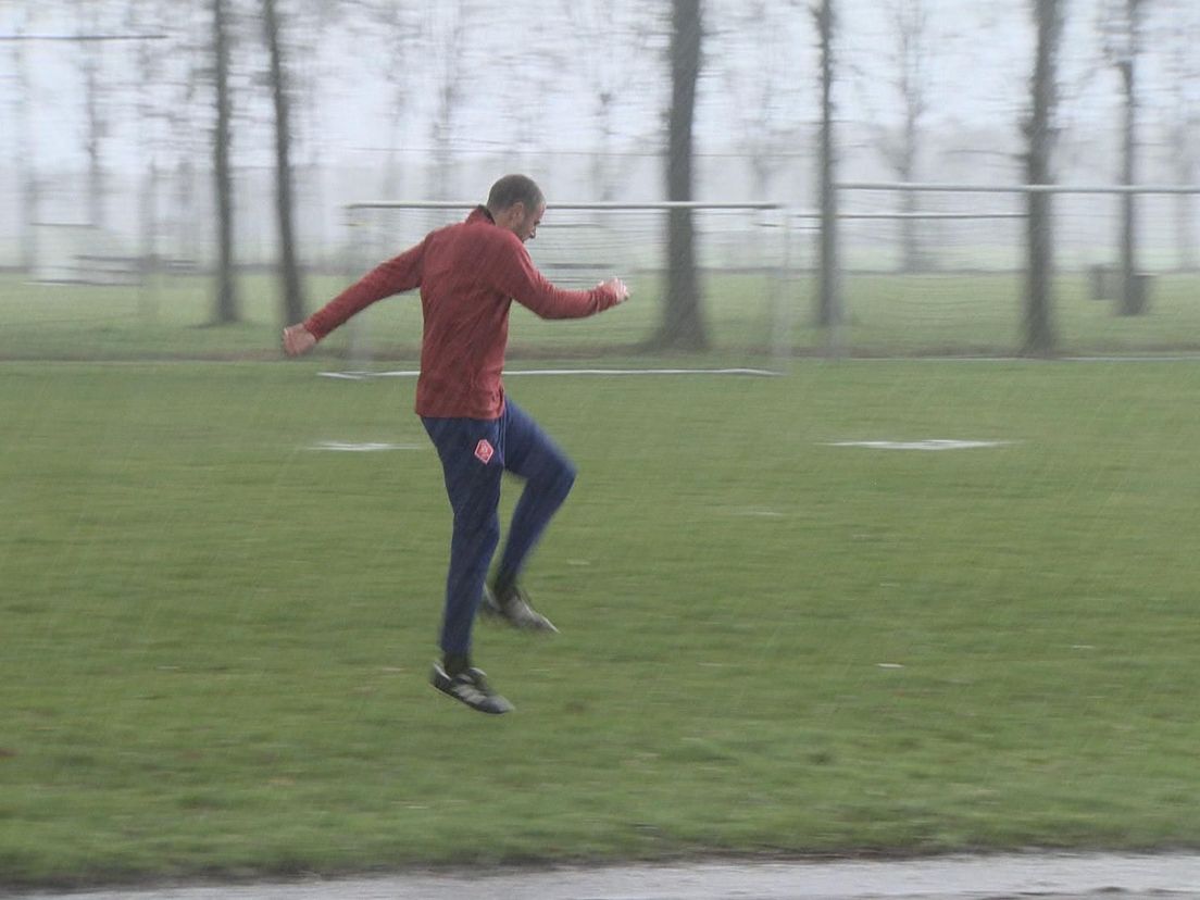 Danny Koevermans doet op een bijveld in Eersel in de regen zijn warming-up als jeugdscheidsrechter