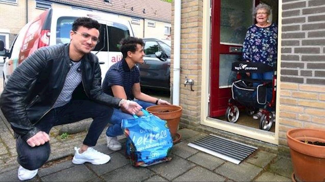 Vrijwilligers Roland en Remco Guijs van Boodschappendienst Alifa Welzijn Senioren leveren boodschappen af bij mevrouw Andres