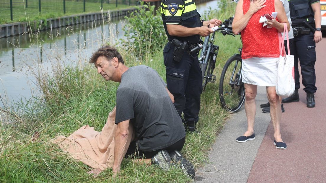 Aart Spiering ondersteunt de man die hij net uit het water heeft gered.
