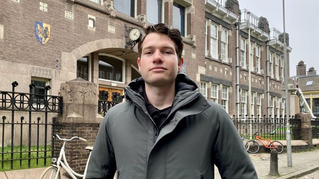 Buurtbewoner Leander Cingöz voor het pand van de voormalige HBS, waar nu zo'n zeventig studenten in wonen.