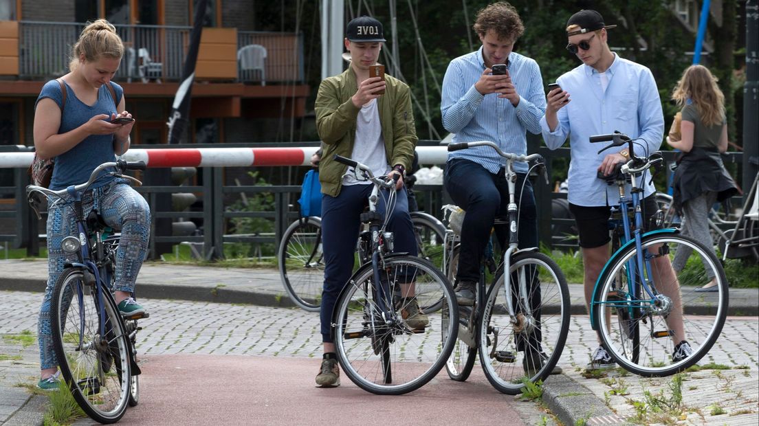 Vier mensen zijn bezig met hun smartphone