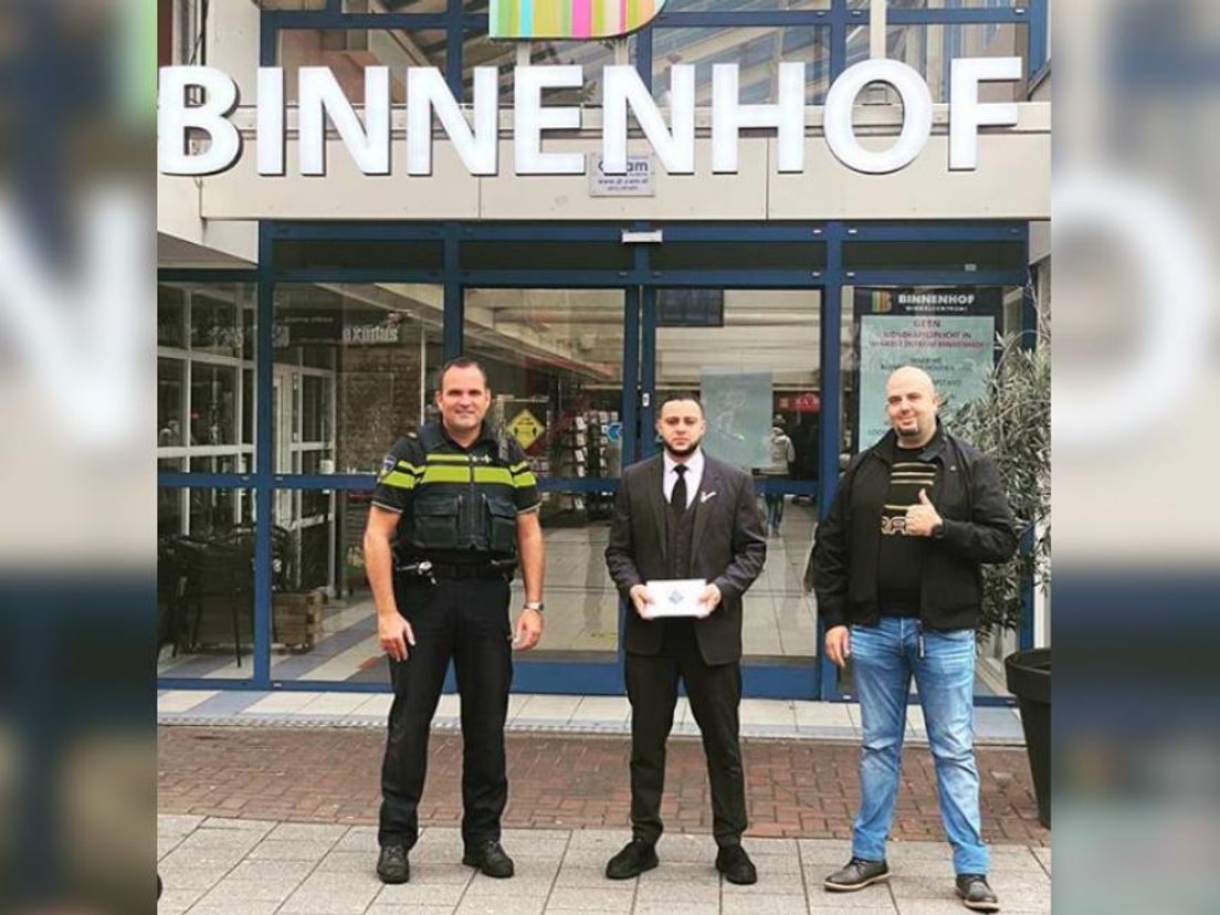 Wijkagent Van Heusden met redder 
Abdessamad en zijn baas bij winkelcentrum Binnenhof