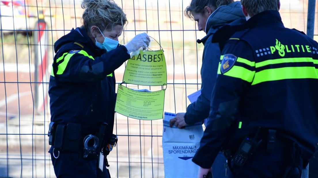 De politie haalt een pamflet weg die bij de asbestdump is achtergelaten
