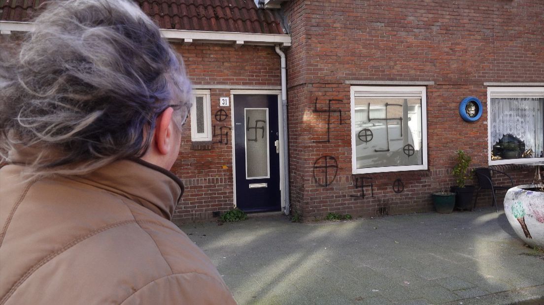 Een buurtbewoonster kijkt geschokt naar de hakenkruizen in de Van Koetsveldstraat