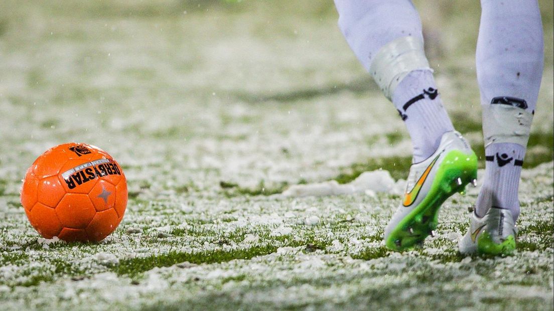 Oranje bal op voetbalveld met sneeuw