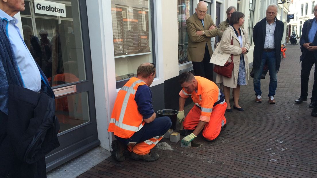De stratenmaker plaatst de struikelstenen in de grond