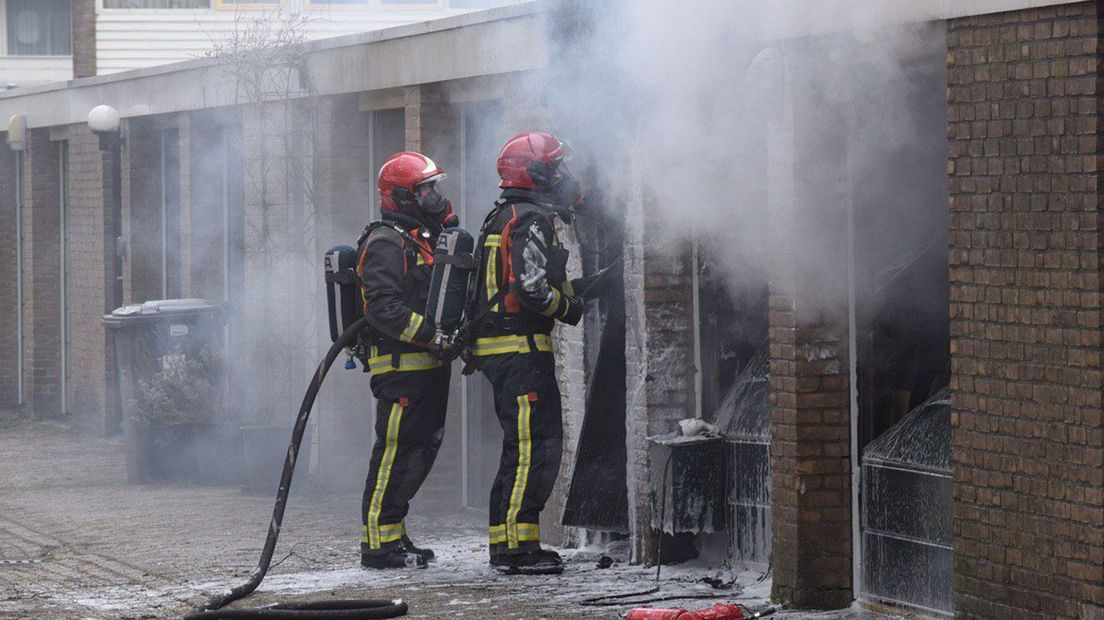 De brandweer bezig met blussen van de garageboxen