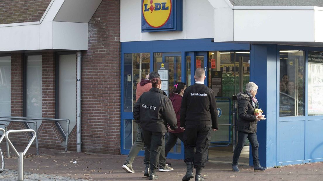 Beveiligers lopen met asielzoekers mee naar een supermarkt