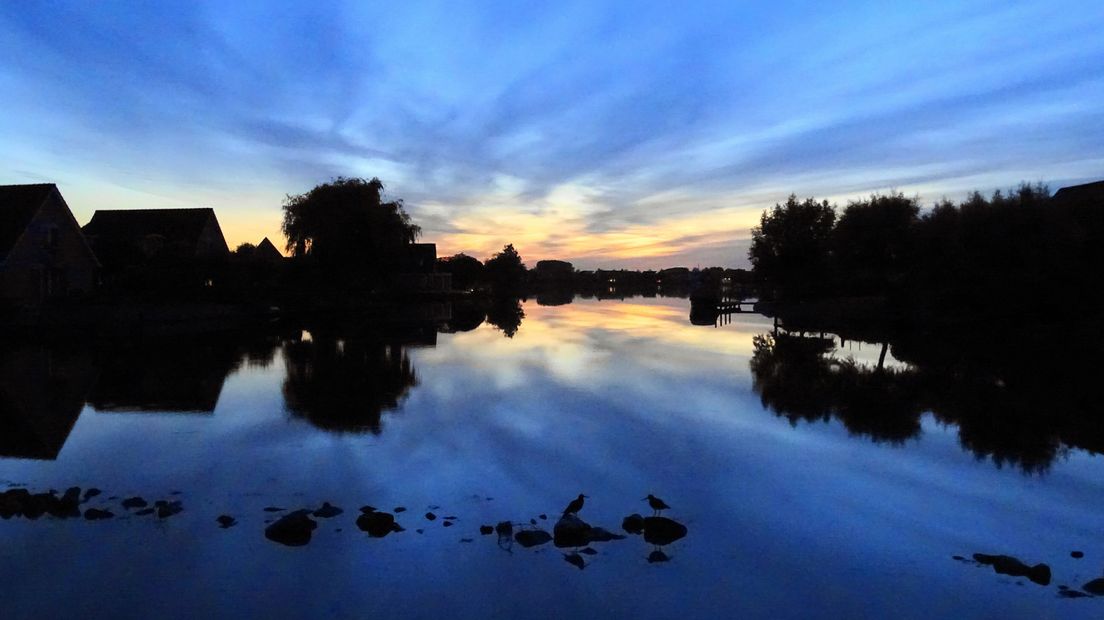Zon gaat onder achter huizen aan het water