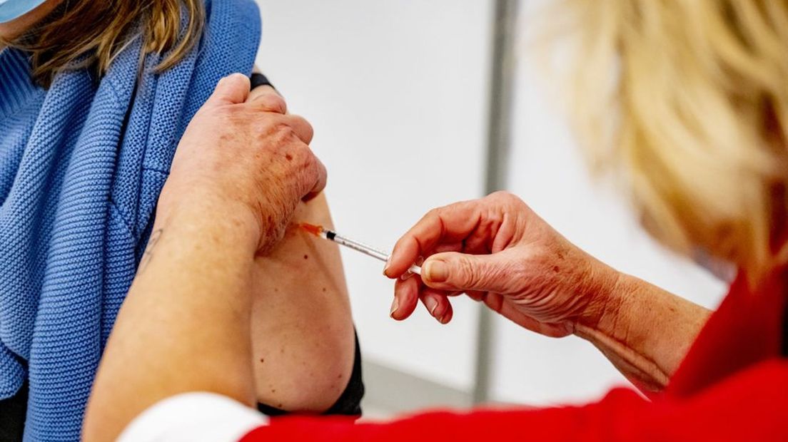 Een GGD-medewerker dient een vaccinatie toe.