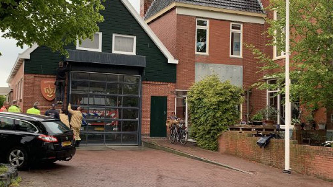 Brandweerlieden in Baflo proberen de kazernedeur handmatig te openen, maar tevergeefs.