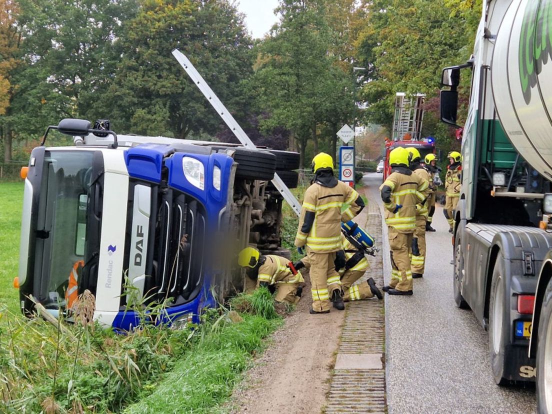 De brandweer controleert de gekantelde kadavervrachtwagen