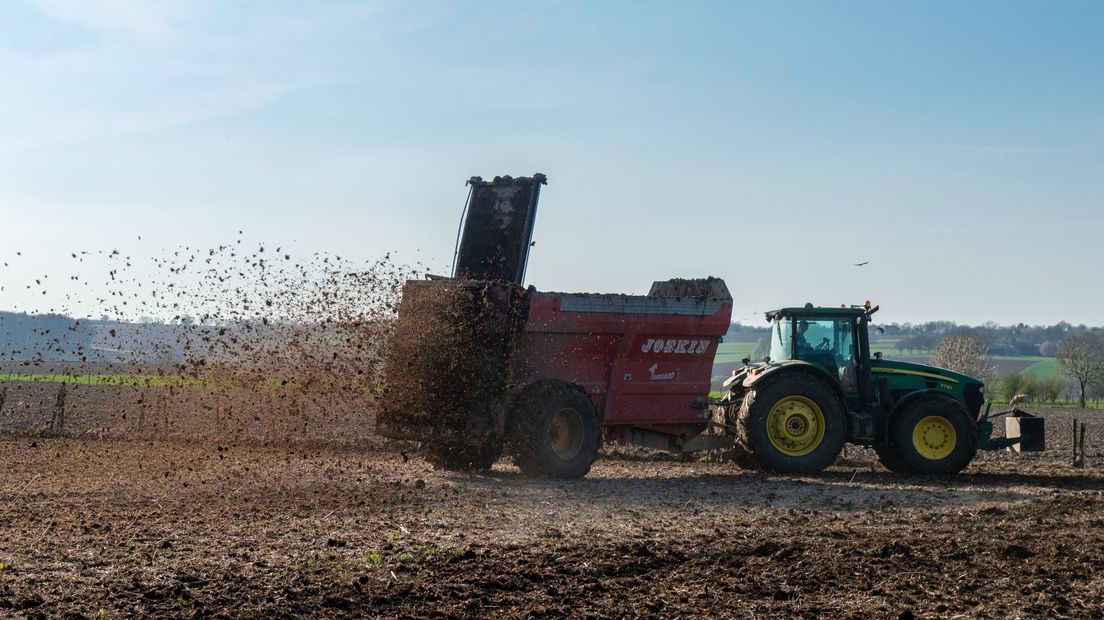 Een boer rijdt mest uit op zijn land