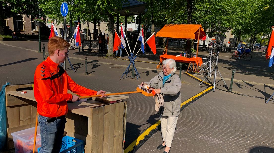 Op de Brink in Baarn worden tompoezen uitgedeeld. Dat gebeurt met gepaste afstand.