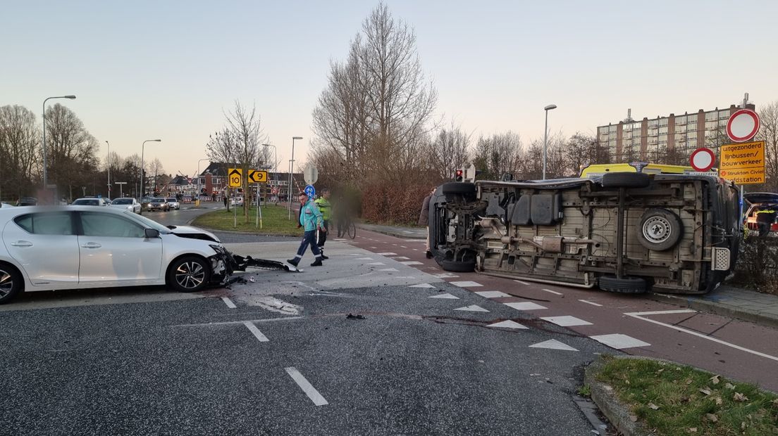 Door de botsing is het busje op de zij beland