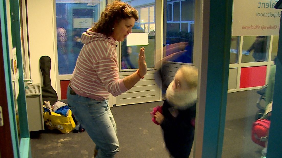 Juf Lesli geeft een leerling bij binnenkomst een high five