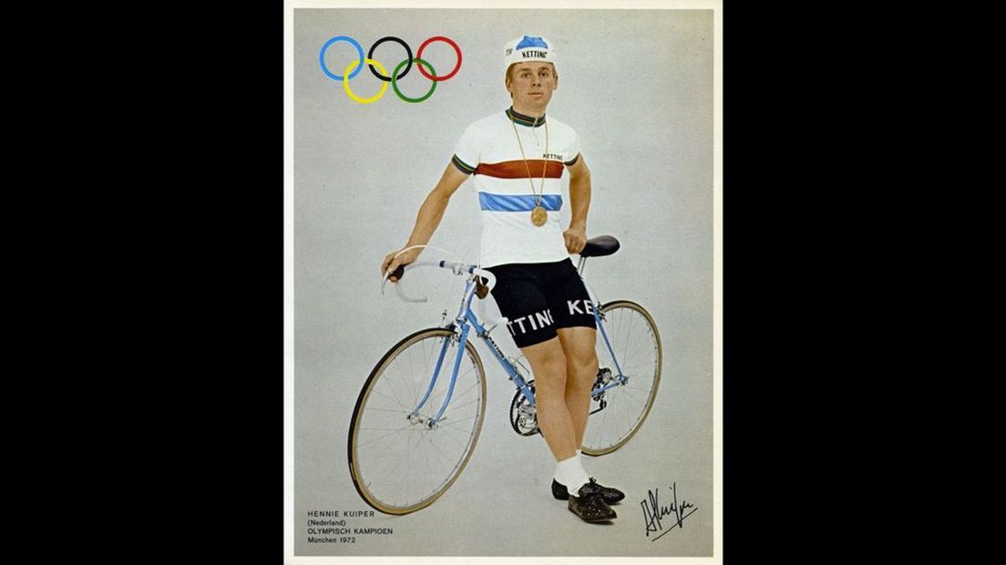Een promotiefoto van Hennie Kuiper met regenboogtrui, gouden plak en Ketting-fiets.