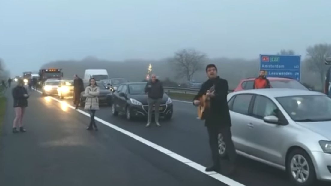 Muzikant Sander Metz met gitaar op de vluchtstrook van de A7