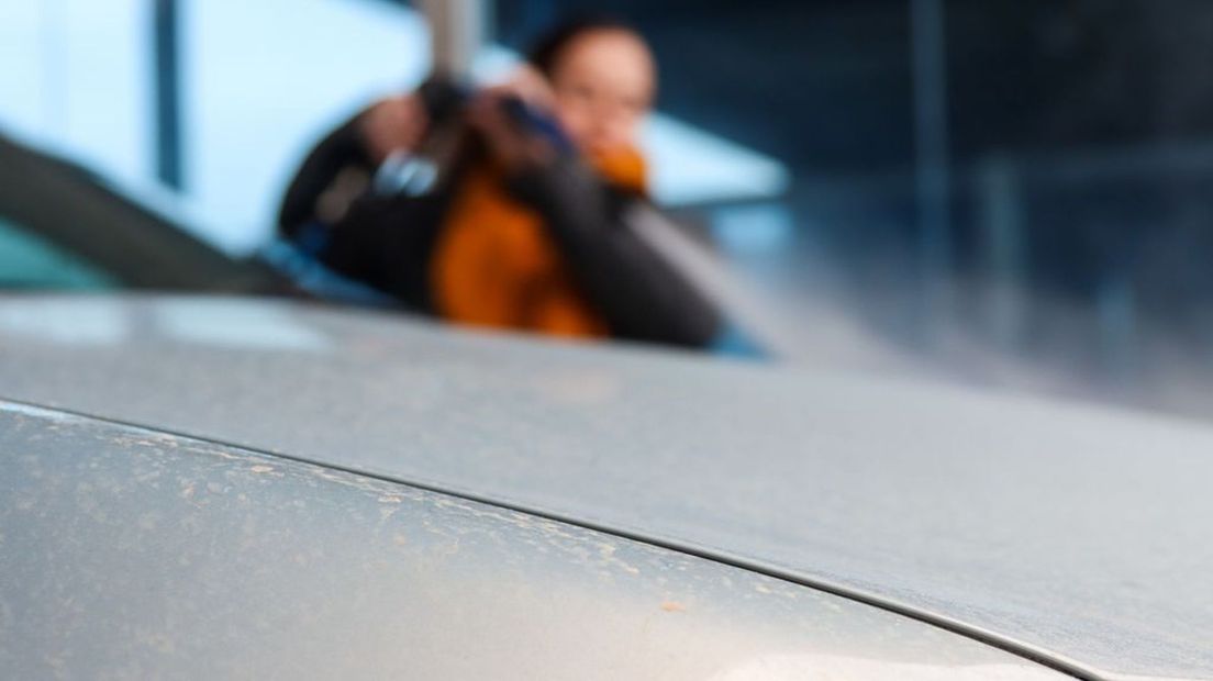 Een vrouw wast het Saharastof van haar auto.