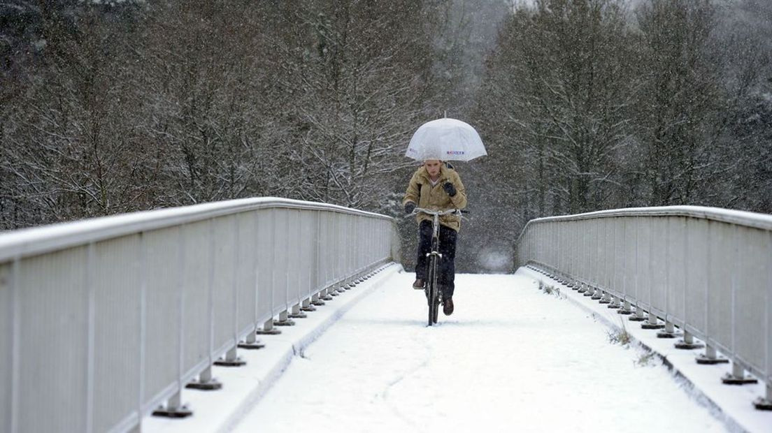 Een fietser rijdt over een besneeuwd fietspad.