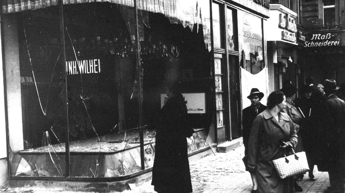 Duitse burgers lopen op 10 November 1938 langs de kapotte etalageruit van een joodse winkelier, nadat de zogeheten Kristallnacht had plaatsgevonden (Rechten: archief ANP)