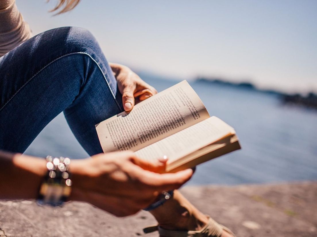 Boek lezen aan de waterkant (foto ter illustratie)
