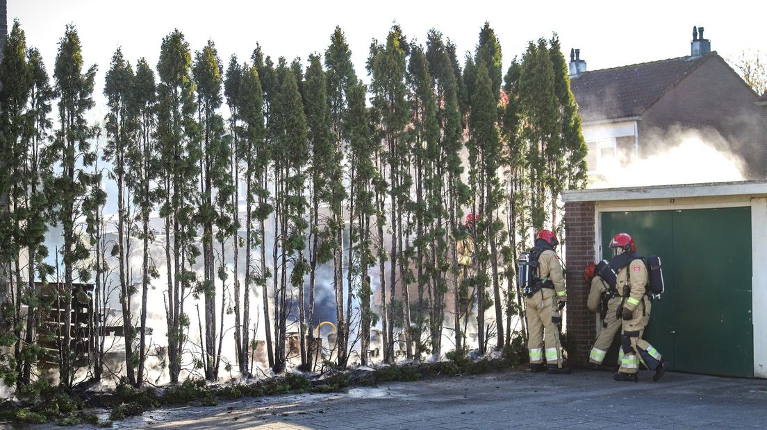 Brandweerlieden blussen de smeulende resten van de coniferen.