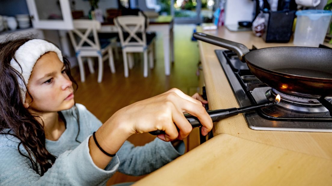 Een vrouw steekt een gaspit aan om een ei te bakken