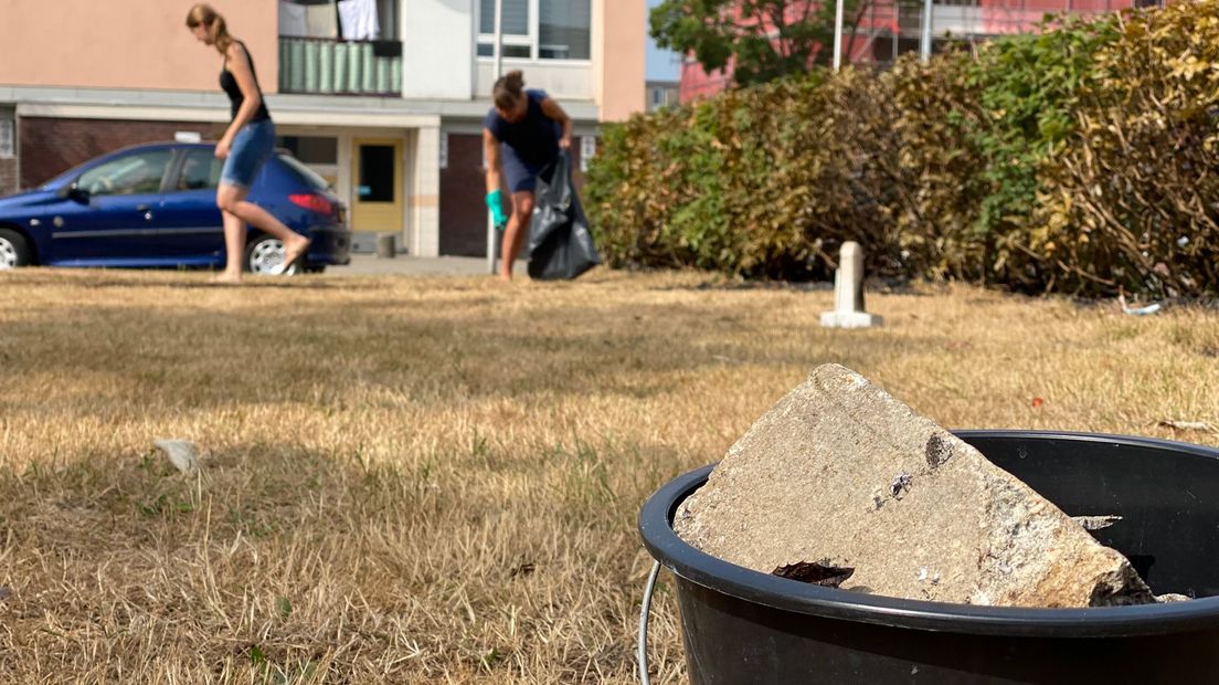 Bewoners ruimen stukken steen op dit op straat lagen.