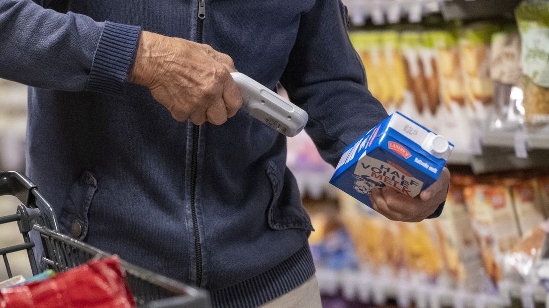 Een man scant een pak melk in de winkel