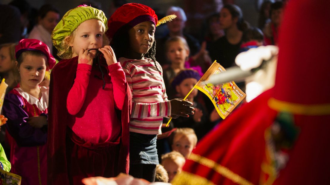 Kinderen, verkleed als pietjes, kijken vol spanning naar Sinterklaas tijdens de viering van 5 december.