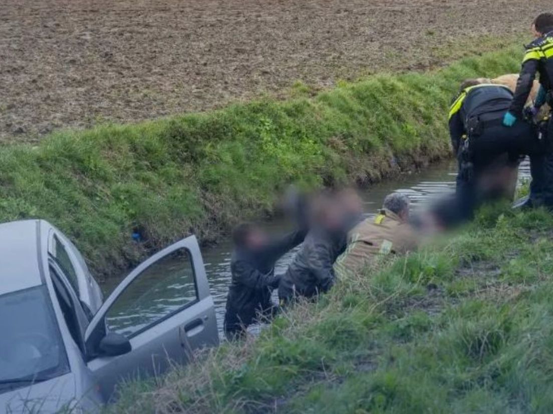 Omstanders en brandweerlieden halen inzittenden uit het voertuig