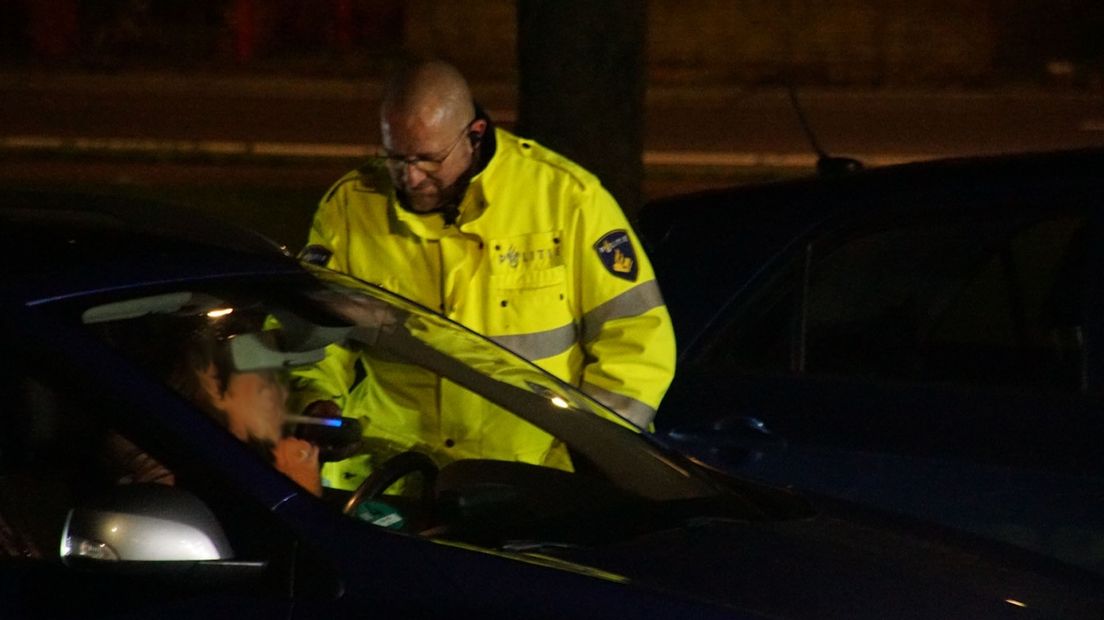 Een agent neemt bij een bestuurder een blaastest af.