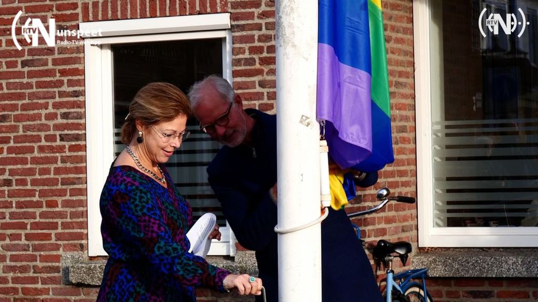 Burgemeester hijst de regenboogvlag.