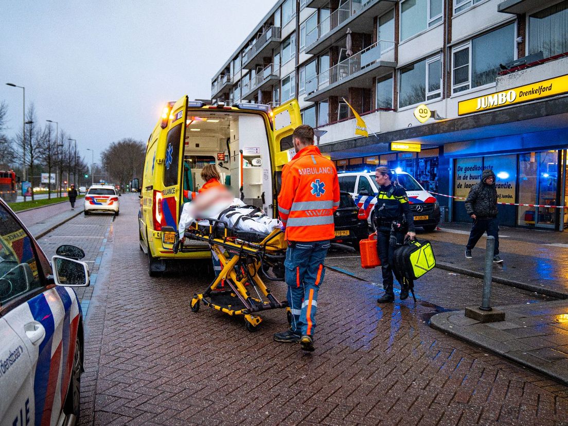 Het slachtoffer van de supermarktoverval wordt in de ambulance gelegd