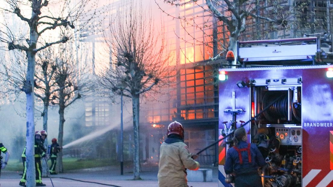 Brandweerlieden bestrijden de vlammen in de school.